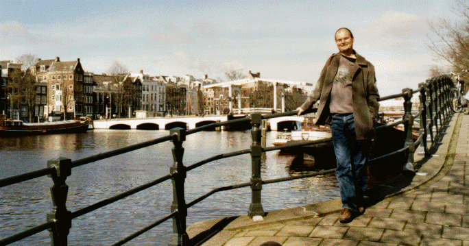 Andrew overlooking the Amstel River with the Maghere Brug behind, Amsterdam, The Netherlands